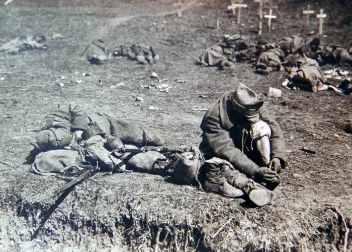 FOTO remarcabilă. ”Pe tălpile infanteriștilor români s-a făcut 1 decembrie 1918”. O imagine hieratică: soldații dorm înveliți cu mantii lângă câteva cruci recente sub care dorm martirii Armatei Regale. În plan apropiat, un soldat își verifică bășicile de la picioare